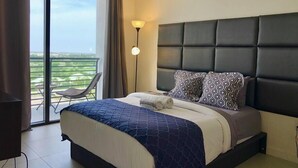 A hotel room with a large bed, a balcony with a chair, and a view of the landscape.