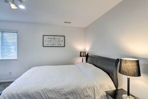 Un dormitorio con cama, lámpara de pared, ventana con persianas y una cita motivacional en la pared.