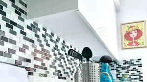 Una cocina con salpicadero de azulejos, una botella de agua azul y un cuadro en la pared.