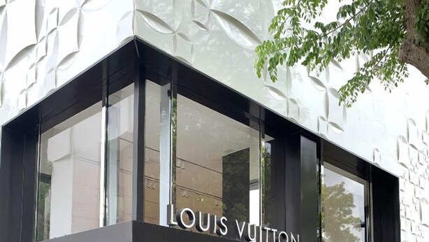 Fasaden på en Louis Vuitton-butik med stora glasfönster och en modern arkitektonisk design.
