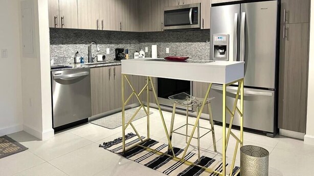 A modern kitchen with stainless steel appliances, a central island, and a microwave above the sink. - A1608 AWESOME Downtown Doral Apartment (Doral)
