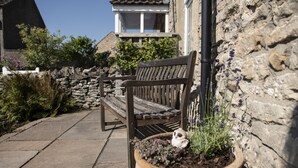 A stone wall, a wooden bench, and a potted plant with a small owl. - Witton View, Bellerby, Yorkshire Dales (Leyburn)