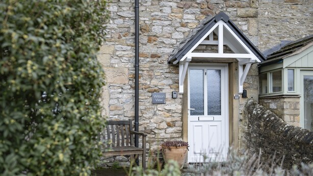 A stone building with a white door, a bench, and a potted plant. - Witton View, Bellerby, Yorkshire Dales (Leyburn)