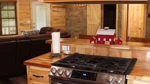 Una cocina con encimera de madera, estufa y un modelo de casa roja.