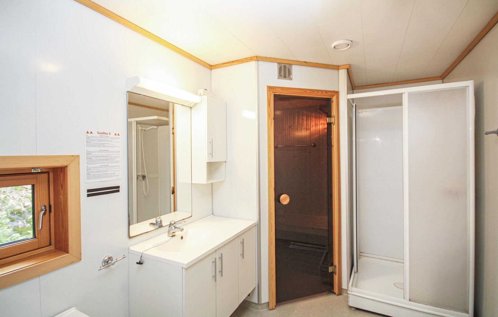 Een badkamer met een witte wastafel, spiegel en douchedeur.