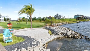 A waterfront property with a paved deck, a small pool, and a beach chair. - Pelican Pier Beach House on Lake Catherine (New Orleans)