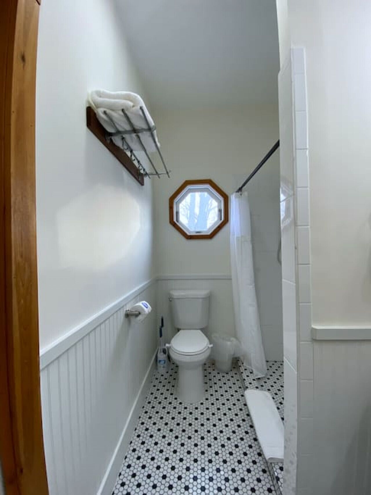 Un baño estrecho con inodoro, ducha y una pequeña ventana.