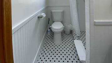 Un baño estrecho con inodoro, ducha y una pequeña ventana.