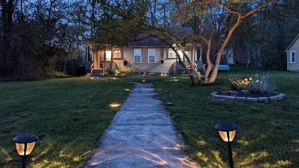 A residential house with a front yard, pathway, and two street lamps.