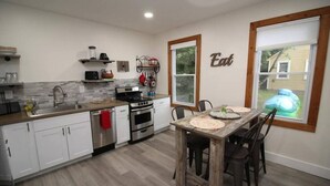 A modern kitchen with white cabinets, stainless steel appliances, and a wooden dining table with placemats.