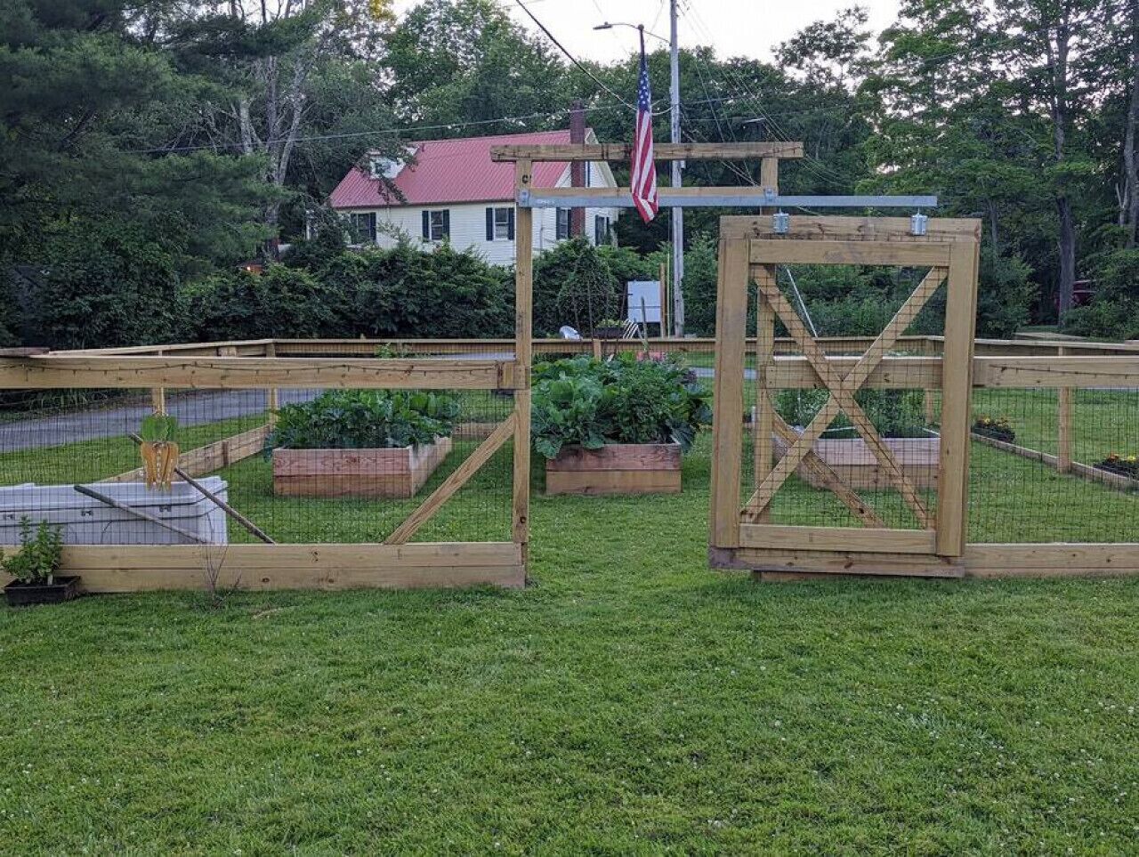 A wooden structure with a metal frame, surrounded by a wire fence, and a flagpole with an American flag.