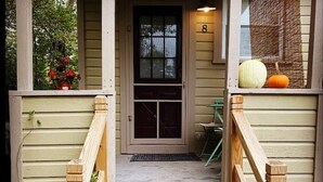 Un escalier en bois mène à une porte sur laquelle est apposé un panneau portant le numéro 8.