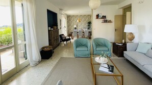 A spacious living room with a sofa, two armchairs, a coffee table, and a dining area in the background. - Elegant and bright apartment with terrace on the waterfront of Aci Trezza (Aci Trezza)