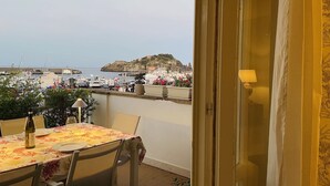 A balcony with a table set for dining, overlooking a marina with boats and a distant island. - Elegant and bright apartment with terrace on the waterfront of Aci Trezza (Aci Trezza)