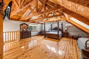 Ein Schlafzimmer mit Holzboden, einem Himmelbett, einem Schminktisch und einem Fenster.