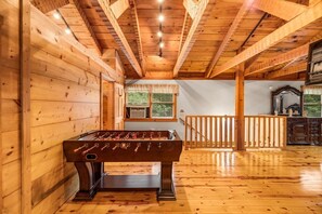 Enjoy a game of foosball in this spacious room with a high ceiling and large window.