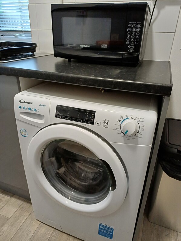 A compact kitchen with a microwave and a front-loading washing machine. - 1 Bedroom apartment with a 5 minute walk into the town. Enclosed garden. (Faversham)