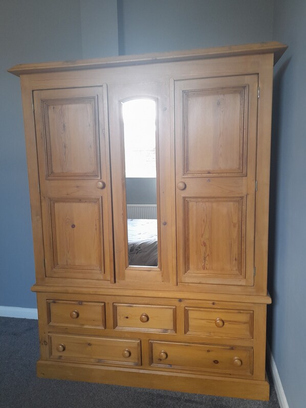 Un aparador de madera con dos puertas y un espejo, que incluye varios cajones y un pequeño estante.