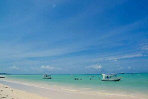 A beach with clear turquoise water, boats, and a sandy shore. - Mombasa beach-Luxury Penthouse Beachfront (Mombasa)