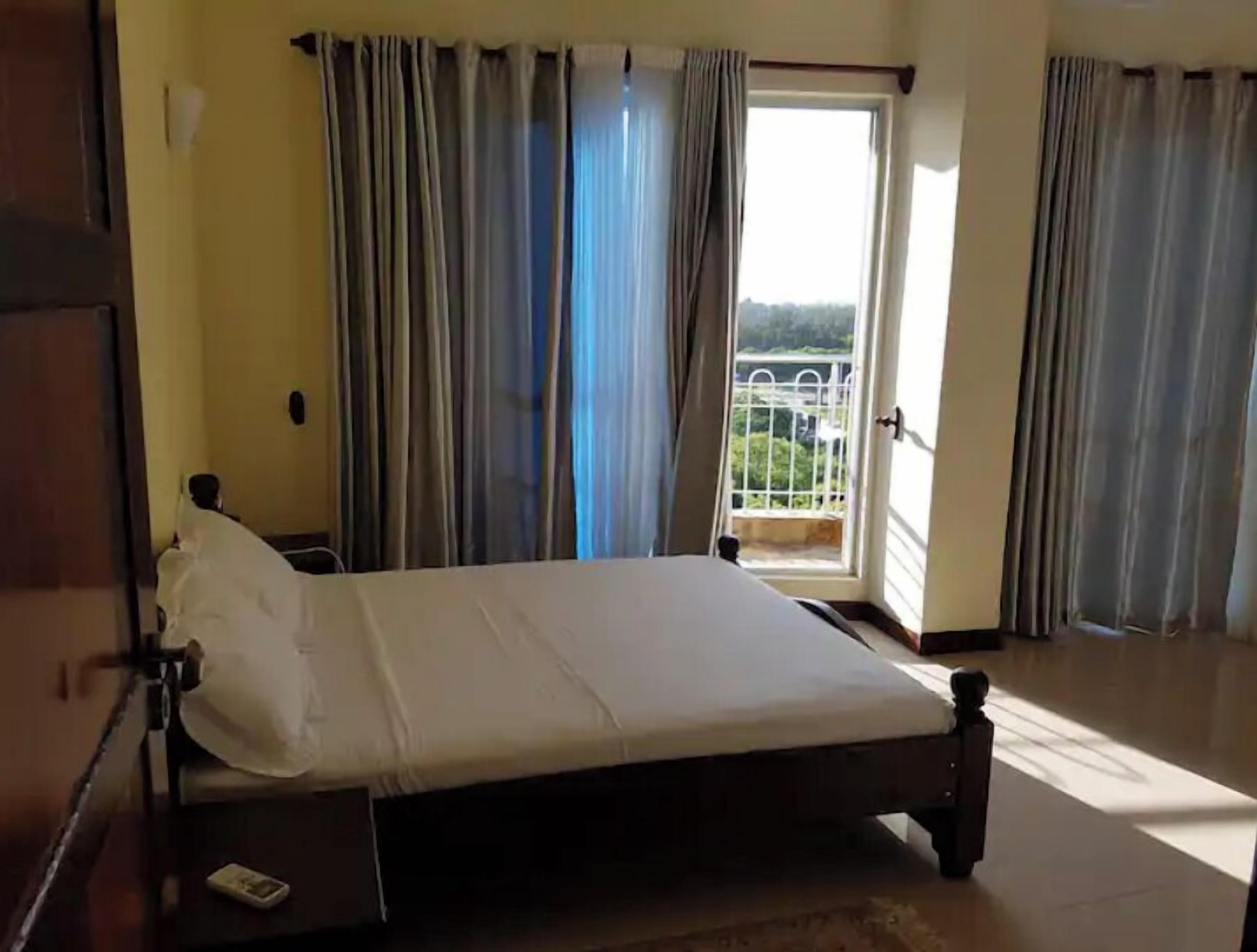 Una habitación con una cama, una puerta y vistas a un balcón.