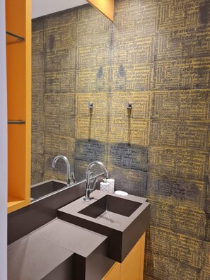 Une salle de bain dotée d’un lavabo et d’un miroir modernes, d’un distributeur de serviettes et d’un mur au motif texturé.
