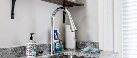 Una cocina con encimera de granito, pileta de acero inoxidable y una estantería doble sobre la encimera.