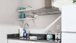Une cuisine moderne dotée d’un plan de travail en granit, d’appareils électroménagers en acier inoxydable et d’une étagère en verre au-dessus de l’évier.