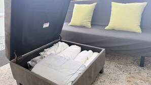 Eine schmale, dunkel gefärbte Aufbewahrungsbox mit Klappdeckel, gefüllt mit ordentlich zusammengelegten weißen Handtüchern.