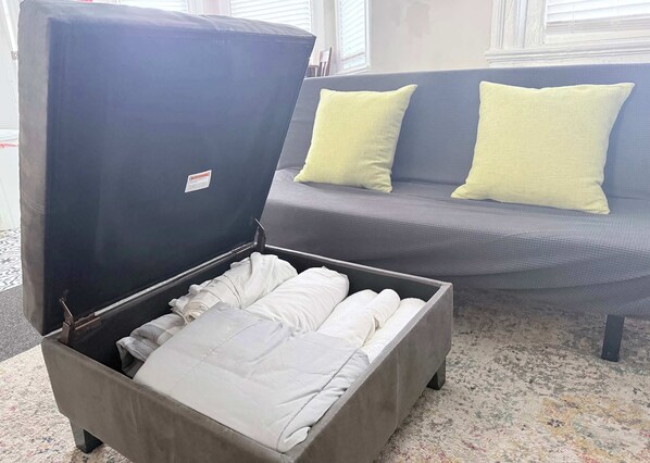 A compact, dark-colored storage box with a hinged lid, containing neatly folded white linens.