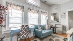 A modern living room with a blue sofa, a patterned chair, a small table, and a refrigerator.