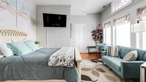 A bedroom with a bed, a TV, a sofa, and a desk.