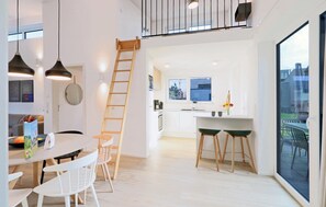 A modern kitchen with white cabinetry, a wooden ladder, and a large window overlooking a cityscape. - Nice Home in Lembruch/dümmer See With 2 Bedrooms, Sauna and Indoor Swimming Pool (Lembruch)