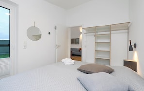 A bedroom with a bed, a wardrobe, a mirror, and a view of a living area. - Nice Home in Lembruch/dümmer See With 2 Bedrooms, Sauna and Indoor Swimming Pool (Lembruch)