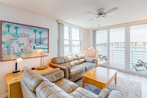 Relax in this stylish living room with a sofa, coffee table, and side table, featuring a beautiful coastal view and a ceiling fan.