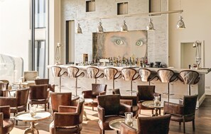 Zona de bar con encimera de mármol, varios taburetes y un espejo grande.