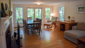 A spacious living area with a dining table, chairs, a sofa, and a desk with a lamp. - Four bedroom home within walking distance to Bayside Brewster beaches! (Brewster)