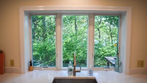 A kitchen with a large window, a stainless steel sink, and a wooden countertop. - Four bedroom home within walking distance to Bayside Brewster beaches! (Brewster)