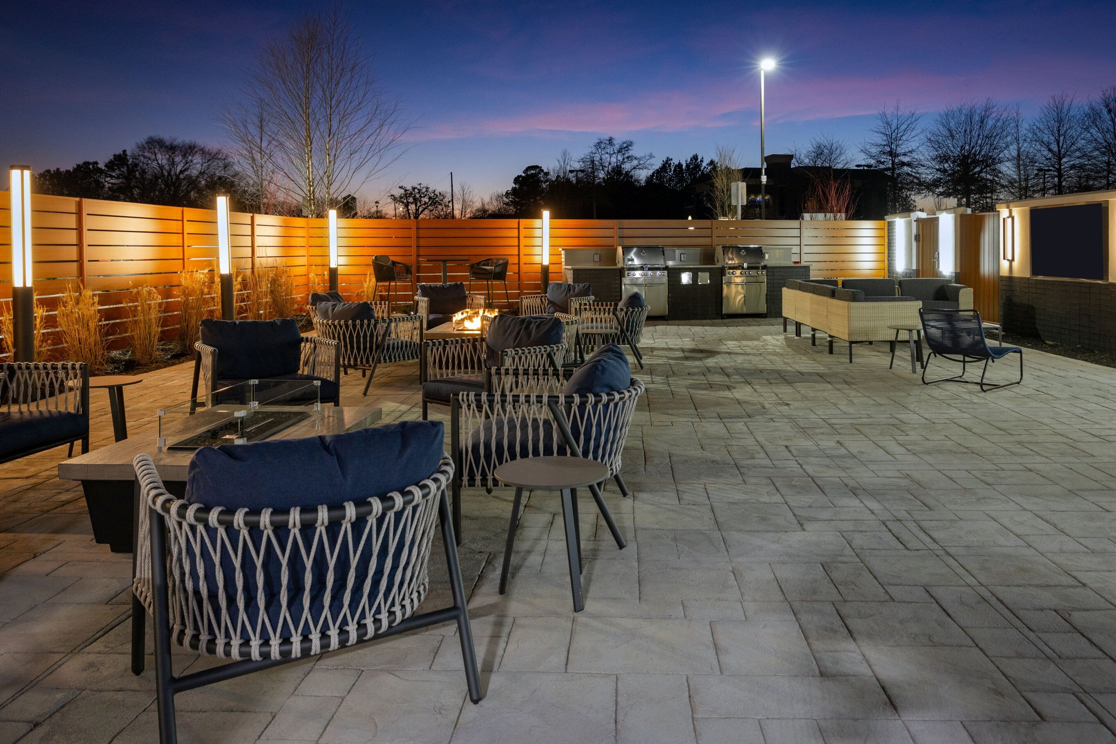Un espacio al aire libre con patio, mobiliario de mimbre, una chimenea y una parrilla.