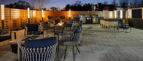 Un espacio al aire libre con patio, mobiliario de mimbre, una chimenea y una parrilla.
