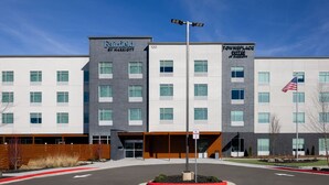 A modern hotel with a central entrance, multiple floors, and a flagpole with an American flag.