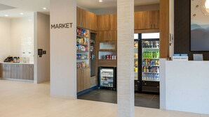 A clean, modern hotel market area with wooden cabinets and refrigerated sections.