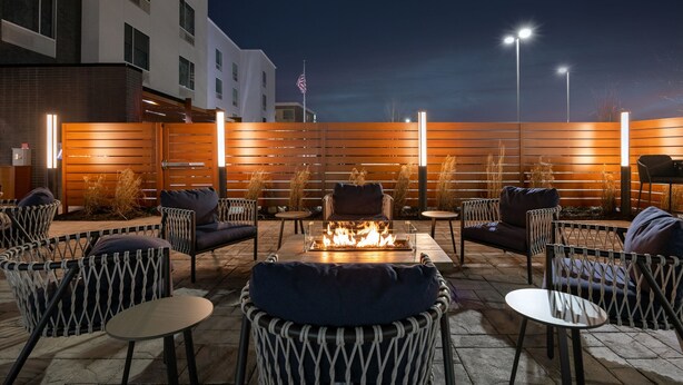 An outdoor seating area with a fire pit, wicker chairs, and tables.
