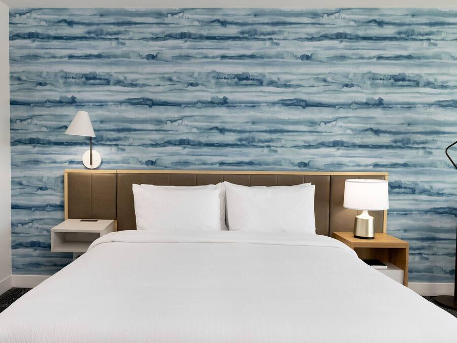 A hotel room with a bed, two bedside tables, and a nightstand.