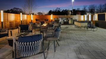 Un patio al aire libre con mobiliario de mimbre, un brasero y una zona de barbacoa.