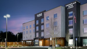 A Fairfield by Marriott Towneplace Suites building with a parking lot and a small landscaped area with a tree.