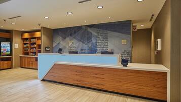 A reception area with a wooden reception desk, a wall with text, and a vending machine.