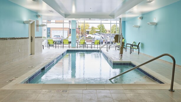 Une piscine intérieure à l’eau claire, entourée de murs et d’un sol recouverts de carreaux.
