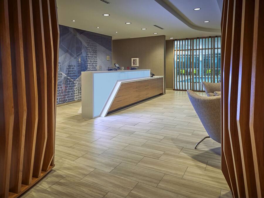 A reception area with a wooden reception desk, a modern chair, and a large window with blinds.
