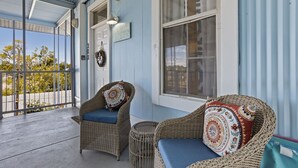 Une véranda meublée de meubles en osier, une petite table et une vue sur l’extérieur.