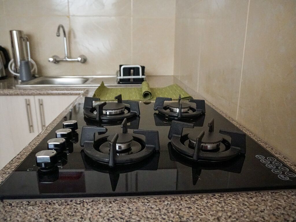 A kitchen with a black stove, a sink, and a faucet.